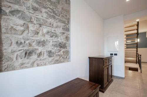 a room with a stone wall and a wooden bench at La Guest House di PIAZZA MOTTA in Albese Con Cassano