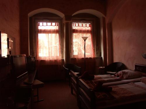 a dark room with two beds and two windows at Hotel Restaurant Toscana Naumburg in Naumburg