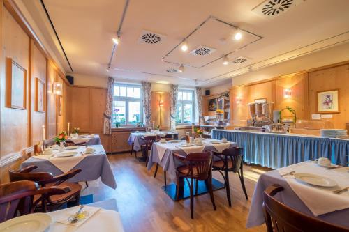 um restaurante com mesas e cadeiras num quarto em Gautinger Hof em Gauting