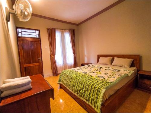 a bedroom with a bed and a table and a window at Famoris Cottages in Tetebatu