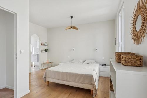 une chambre blanche avec un lit et un miroir dans l'établissement Family home, à Romainville