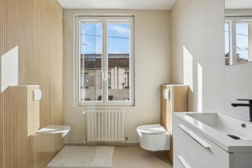 une salle de bain avec toilettes, lavabo et fenêtre dans l'établissement Family home, à Romainville