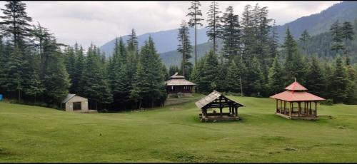 a green field with some gazebos and trees at Ch'i Soulstone HomeStay in Sainj