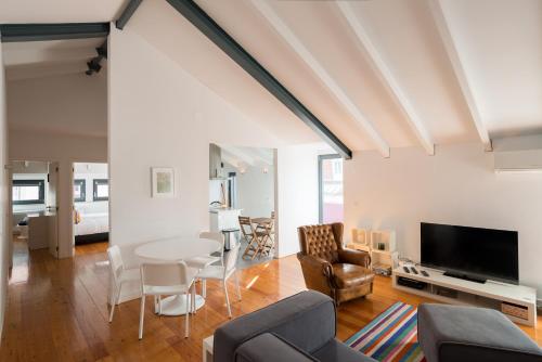 sala de estar con mesa, sillas y TV en FLH Bairro Alto Luxus Flat, en Lisboa