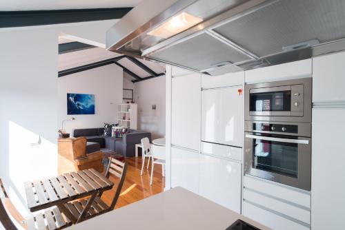 cocina con armarios blancos y sala de estar. en FLH Bairro Alto Luxus Flat, en Lisboa
