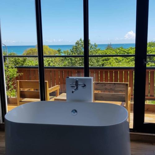 a bath tub in a room with a view of the ocean at The Red Hotel in Nanwan