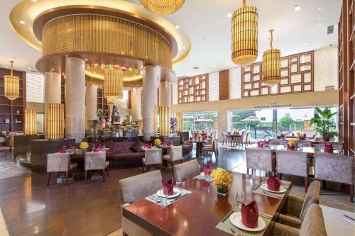 a restaurant with tables and chairs and a bar at Ramada Shenzhen Baoan in Bao'an
