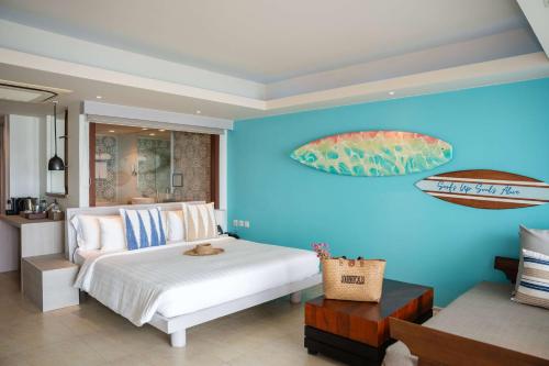 a bedroom with a blue wall with a bed and two surfboards at Zenmaya Oceanfront Phuket, Trademark Collection by Wyndham in Patong Beach