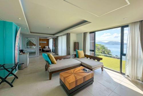 a living room with a couch and a large window at Zenmaya Oceanfront Phuket, Trademark Collection by Wyndham in Patong Beach
