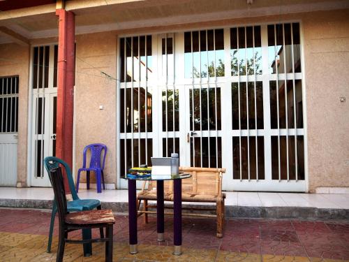 une table et des chaises assises devant un bâtiment dans l'établissement Manuhie Backpackers Lodge, à Baher Dar