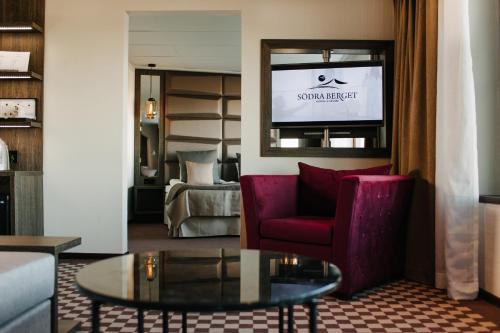 a living room with a red chair and a tv at Hotell Södra Berget in Sundsvall