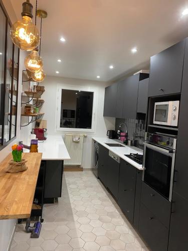 une cuisine avec des armoires noires et une table en bois dans l'établissement Beautiful 2 rooms, near Paris, à Rueil-Malmaison