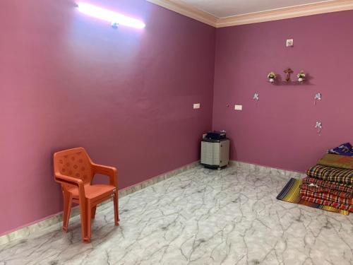 a room with purple walls and a chair and a bed at Bethel Homestay Honnavar in Honāvar