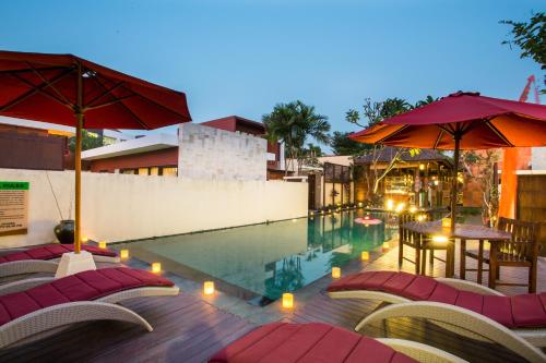 una piscina con sillas y sombrillas junto a un edificio en Jay's Villa Umalas, en Canggu