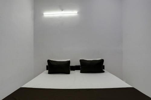 a bed with two black pillows in a white room at Hotel O KAVYA RESIDENCY in Alīgarh