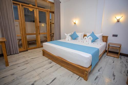 a bedroom with a large bed with blue and white pillows at MJ Haven Point in Ahangama