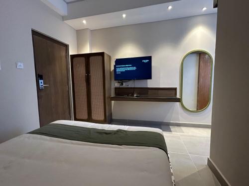 a bedroom with a bed and a flat screen tv at Hotel Kalos in Mahabalipuram