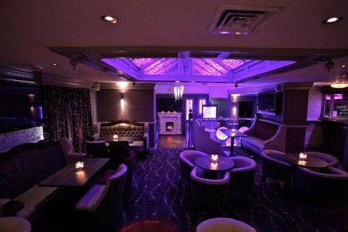 a room with purple lighting and couches and tables at Greenvale Hotel in Cookstown