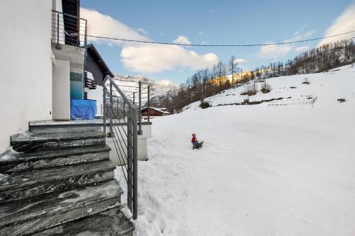 a person on a snowboard in the snow next to a building at Le rêve d'Emilie - Family house in Valtournenche