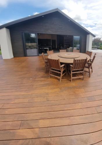a patio with a table and chairs on a deck at Lake Opuha House in Ashwick Flat