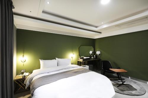 a bedroom with a white bed and a green wall at El Tower Hotel in Gunsan