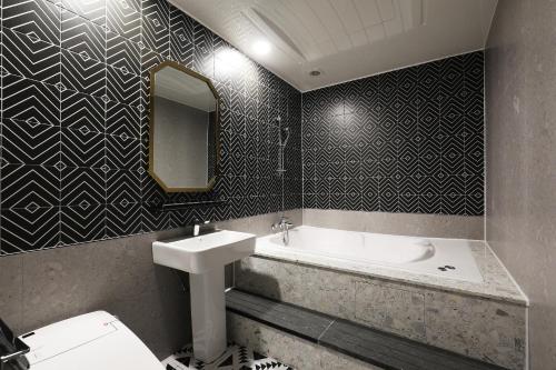 a bathroom with a sink and a tub and a mirror at El Tower Hotel in Gunsan