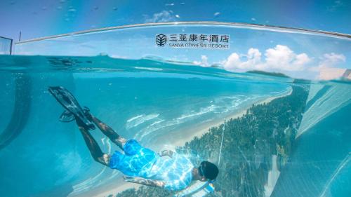 a man is swimming under the water in a glass aquarium at Sanya Conifer Resort in Sanya