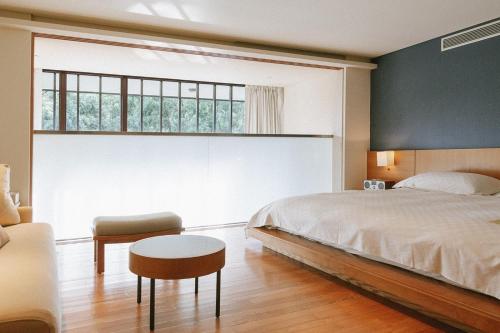 a bedroom with a bed and a chair and a window at Hotel Royal Chiao Hsi in Jiaoxi