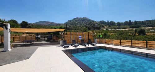 a swimming pool with chairs and a table at לוסטלה ווילה in Ein Kinya
