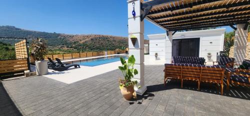 a patio with two benches and a swimming pool at לוסטלה ווילה in Ein Kinya