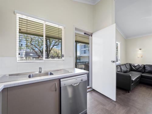 a kitchen with a sink and a couch in a room at Mandalay Holiday Resort and Tourist Park in Busselton