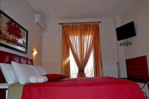 a bedroom with a red bed and a window at Anesis in Ioannina