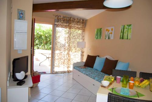 a living room with a couch and a tv at Lagrange Grand Bleu Vacances – Résidence Les Jardins de Neptune in Saint-Cyprien