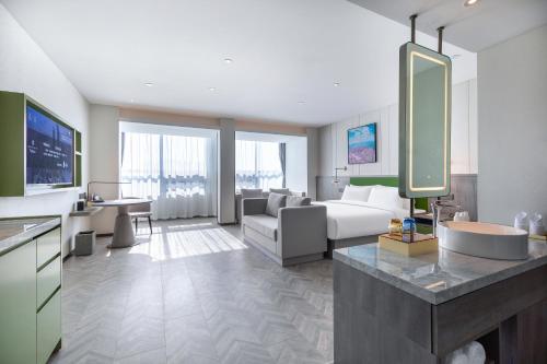 a hotel room with a bathroom and a living room at Mehood Lestie, Qingdao Qingdao Jiaodong Airport Jiaozhou Baolong Plaza in Jiaozhou