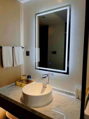 a bathroom with a sink and a large mirror at Mehood Lestie, Qingdao Qingdao Jiaodong Airport Jiaozhou Baolong Plaza in Jiaozhou