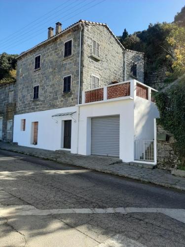 - un ancien bâtiment en pierre avec un garage situé devant dans l'établissement Grande Maison de Village, à Sollacaro