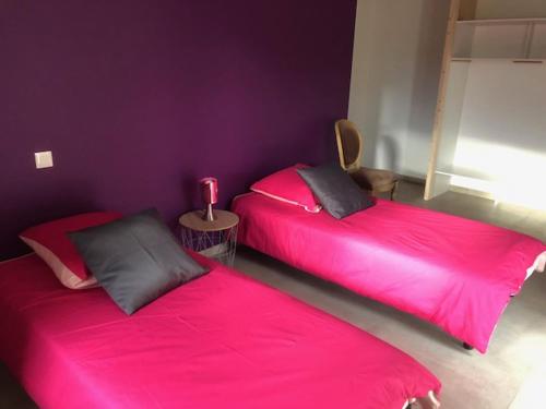 deux lits dans une chambre avec des draps roses dans l'établissement Le GIte de Lavalette, à Lapte