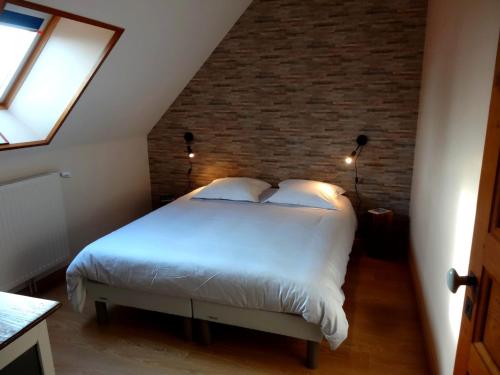 a bedroom with a white bed with a brick wall at Gites de Gondières in Saint-Éloi
