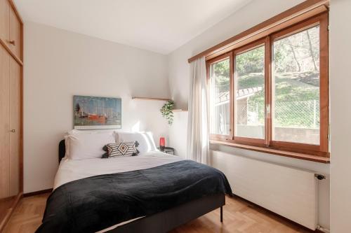 a white bedroom with a bed and a window at Miralago by Quokka 360 - flat in the gulf of Melano in Melano