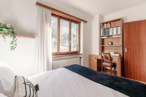 a bedroom with a bed and a desk and a window at Miralago by Quokka 360 - flat in the gulf of Melano in Melano