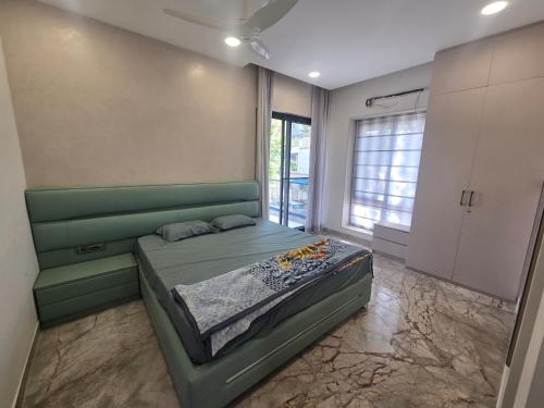 a bedroom with a green bed and a large window at Satish Villa in Hyderabad
