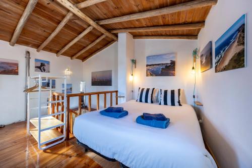 a bedroom with a large white bed and wooden ceilings at Casa Azul - Aljezur Town in Aljezur