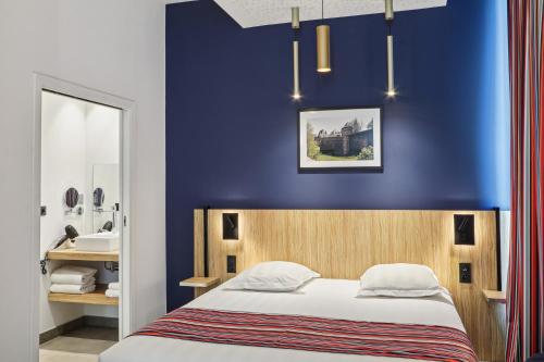 a bedroom with a blue wall and a bed at Akena Nantes Rezé Aéroport in Rezé