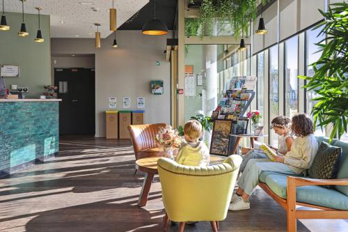a family sitting in chairs in the lobby of a store at Akena Nantes Rezé Aéroport in Rezé