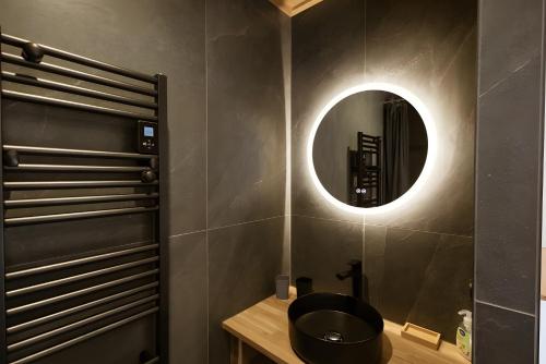 Un baño con un lavabo negro y un espejo. en Chalet Le Strato, en Valloire