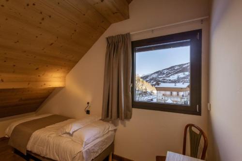 Un dormitorio con una cama y una ventana grande. en Chalet Le Strato, en Valloire
