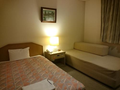 a hotel room with a bed and a night stand with a lamp at Hotel Lakeland Hikone in Hikone