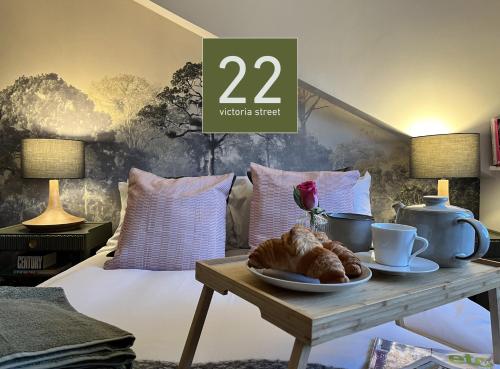 a table with a plate of croissants on a bed at Boutique style cosy cottage in Ellesmere