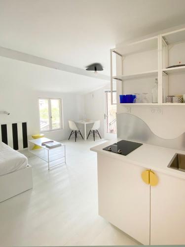 - une cuisine blanche avec des placards blancs et une table dans l'établissement Joli studio vue sur Saône, à Caluire-et-Cuire