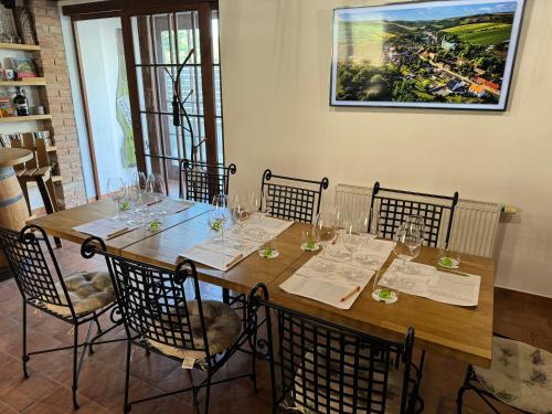 a long wooden table with chairs and wine glasses at Žabinec - penzion, vinotéka in Kurdějov